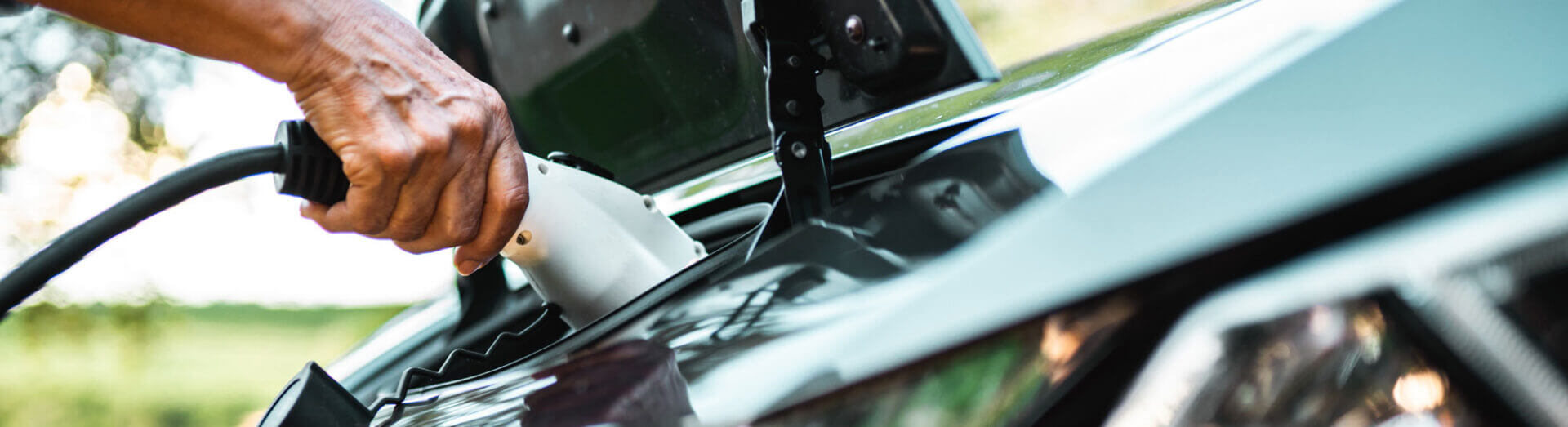 Human Hand Is Holding Electric Car Charging Connect To Electric